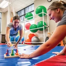 Two students participating in a sensory and motor skills assessment in an occupational therapy classroom.